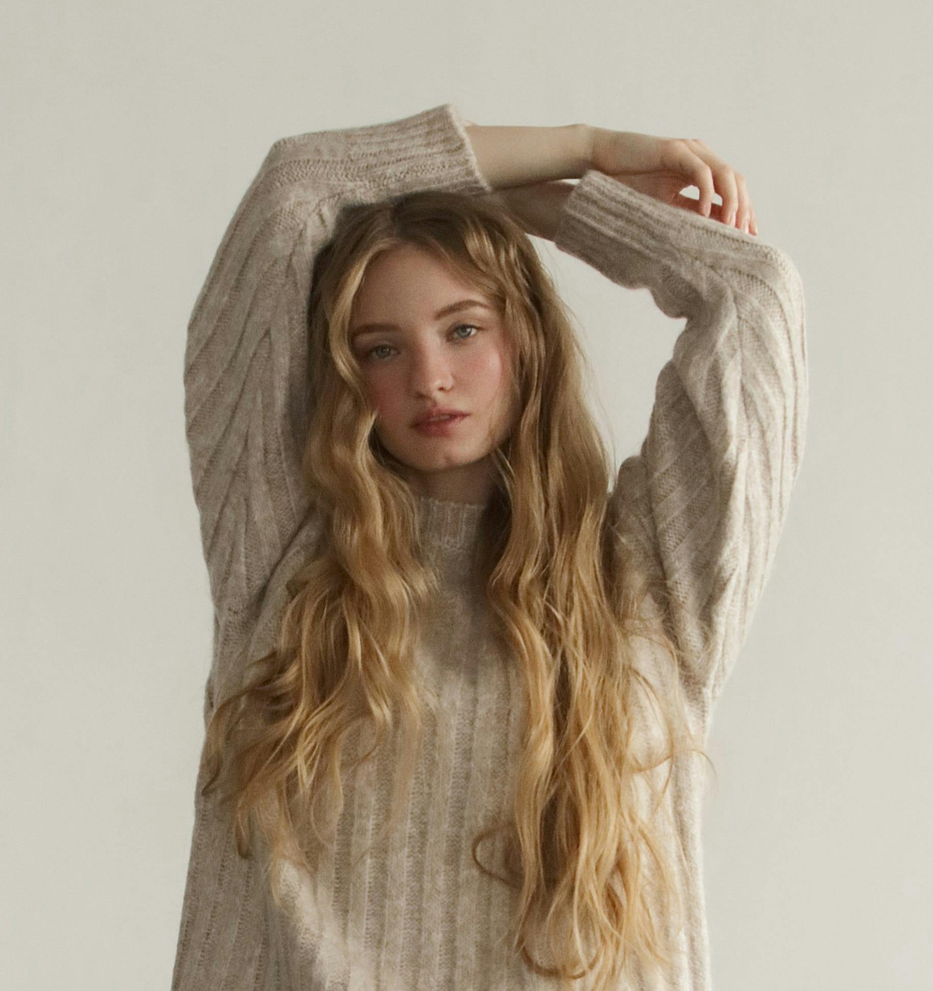 woman with long blonde hair and a sweater on