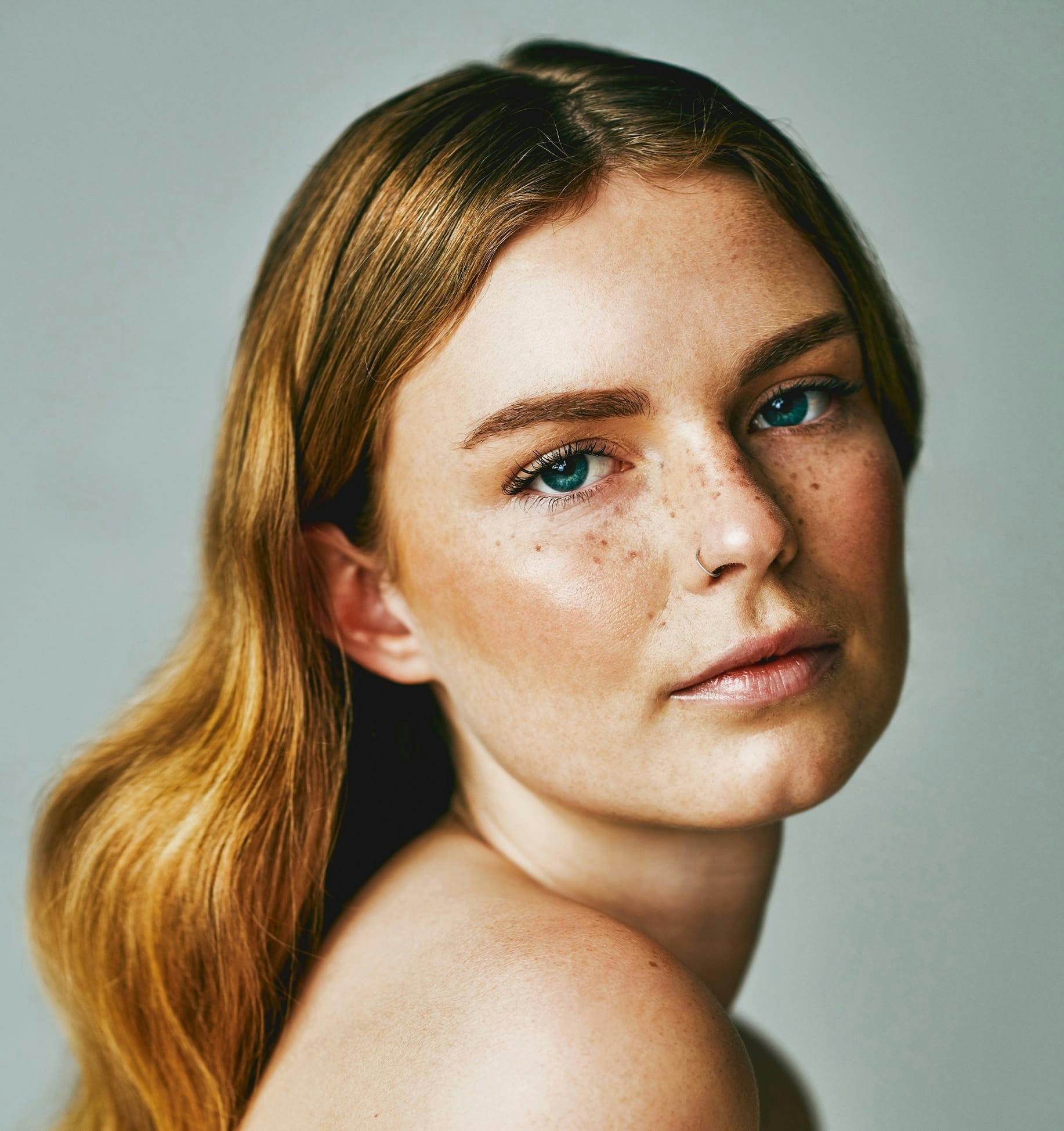 blond woman with freckles and blue eyes posing for a picture