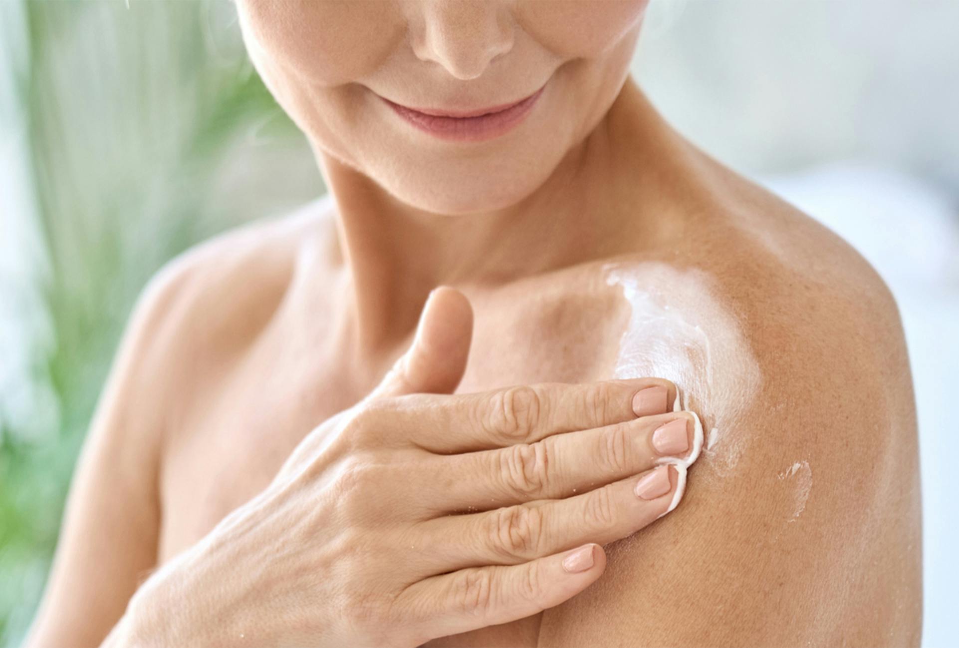 Woman putting lotion on her shoulder
