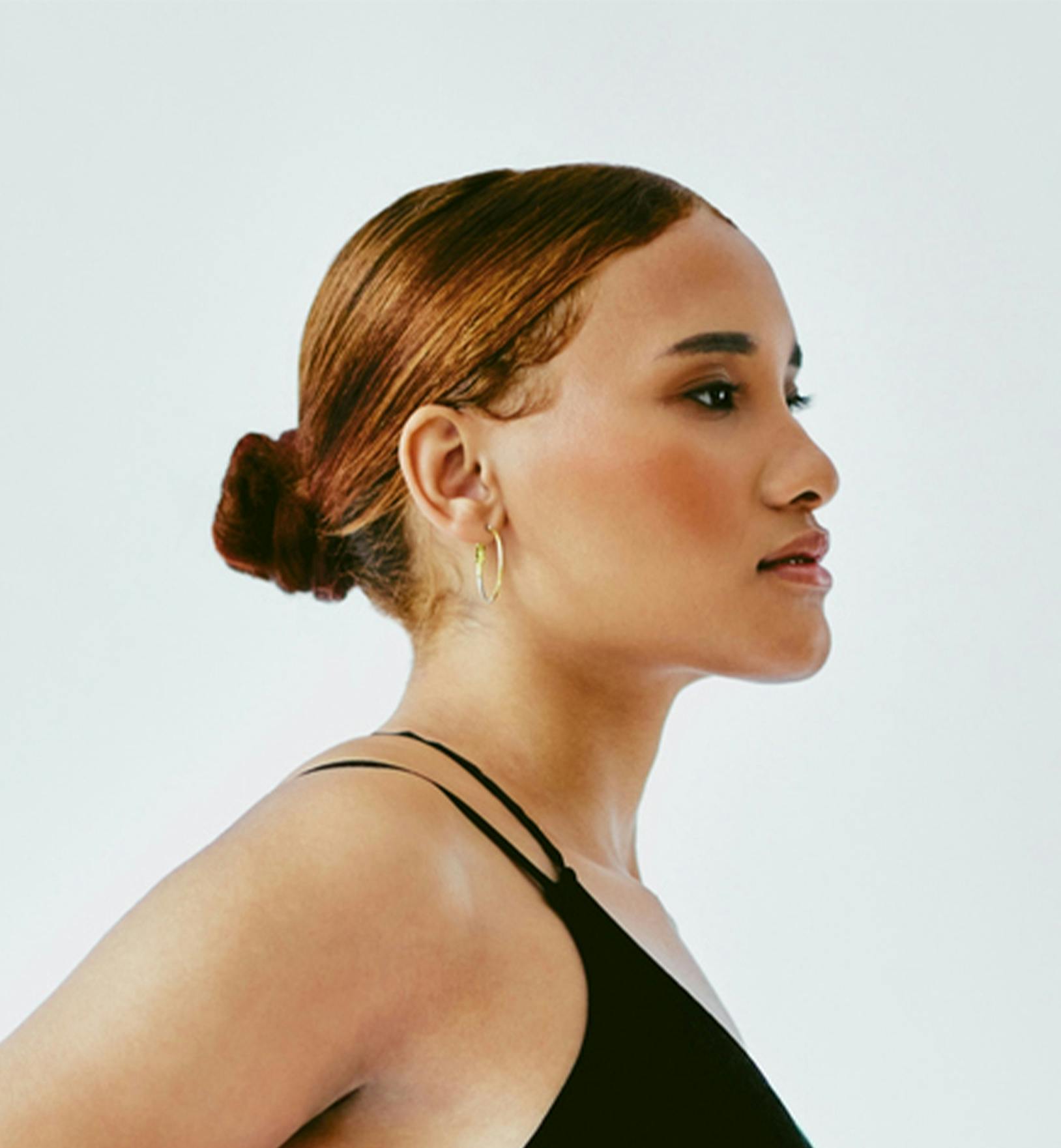 person with red hair in a slicked back bun