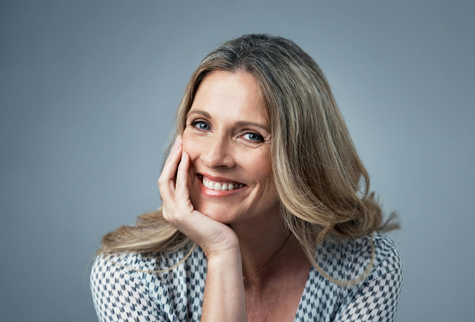 woman smiling while resting her face on her hand