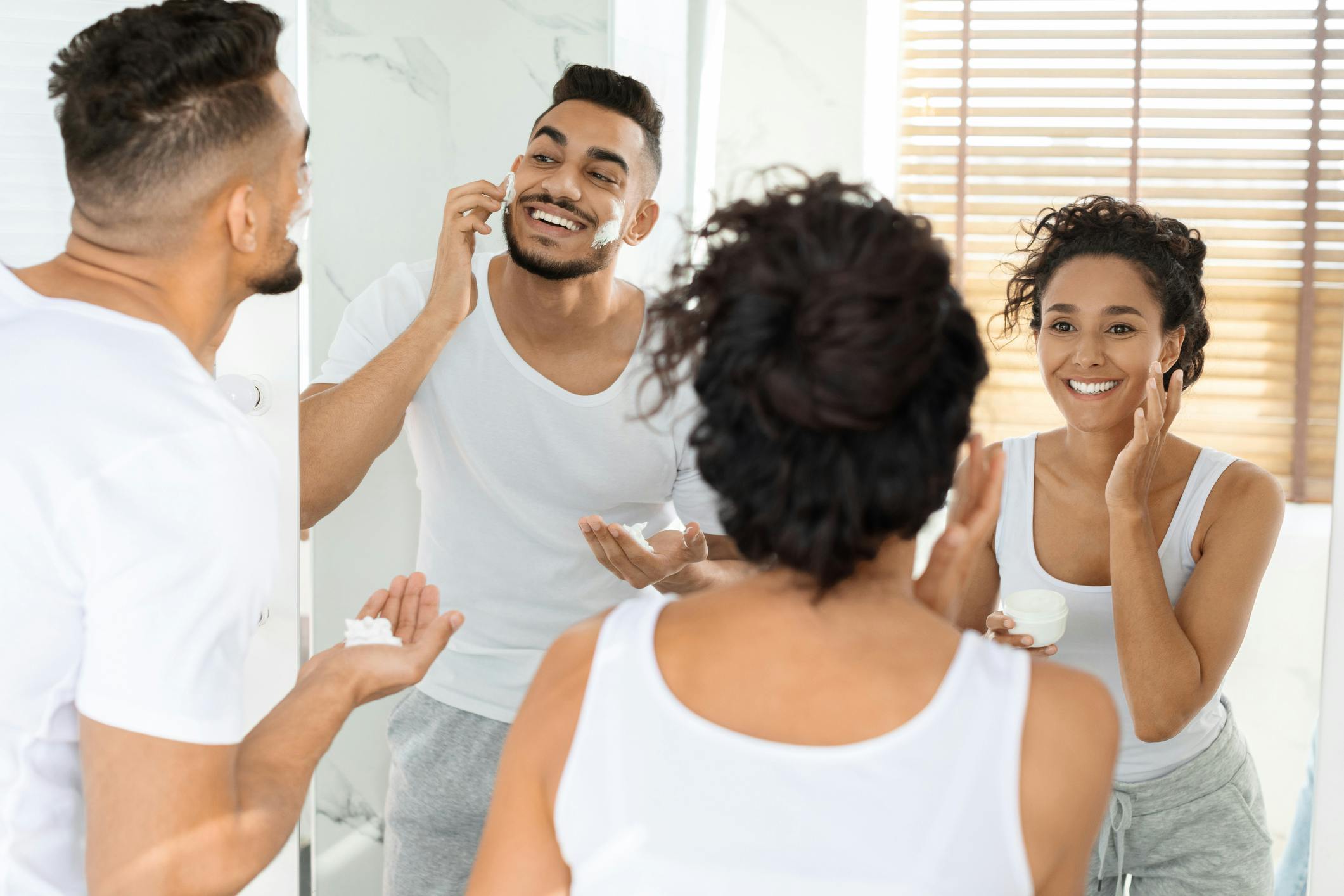 Man and Women doing skincare in front of a mirror
