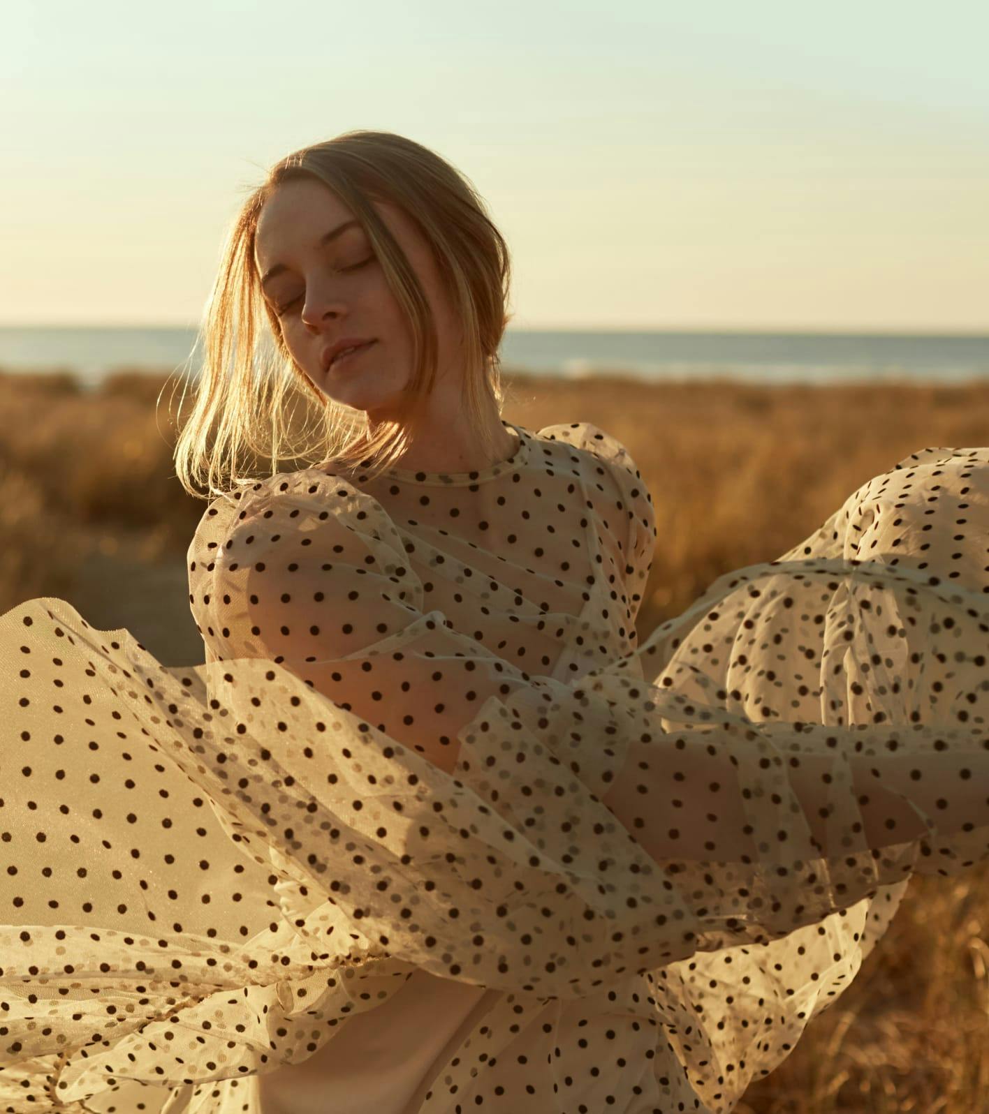 Pretty young woman dancing in a polkadot dress.