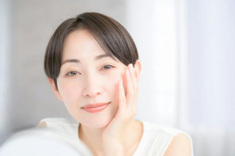 woman with clear skin caressing her face