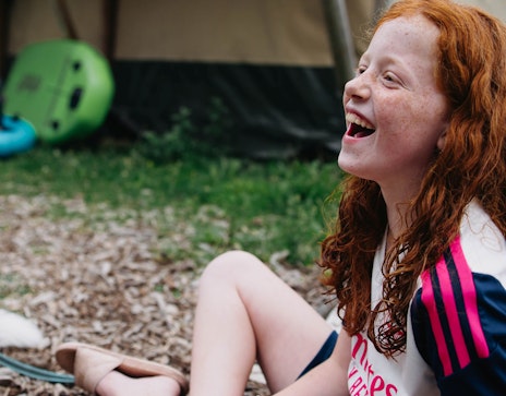 Op deze afbeelding is een lachend meisje te zien die lol heeft tijdens het zomerkamp Breinspoken