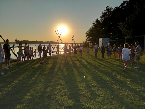 Op deze afbeelding is te zien hoe de groep tijdens het zomerkamp Breinspoken een kennismakingsspelletje aan het doen is bij zonsondergang.