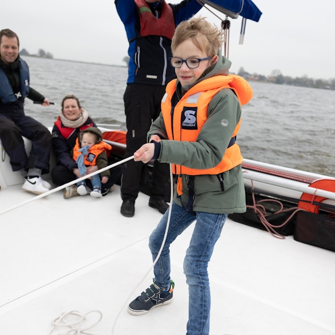 Op deze afbeelding is Luuk te zien die aan het zeilen is met zijn papa met dementie en zijn moeder en broertje.