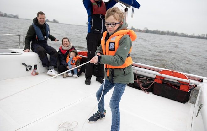 Op deze afbeelding is Luuk te zien die aan het zeilen is met zijn papa met dementie en zijn moeder en broertje.