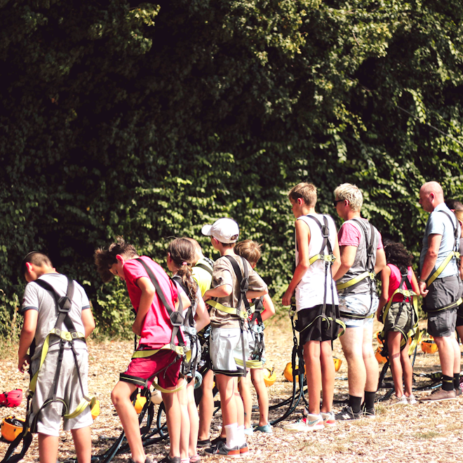 Op deze afbeelding is te zien hoe de groep zich klaarmaakt om te gaan klimmen in het klimpark tijdens het zomerkamp Breinspoken.