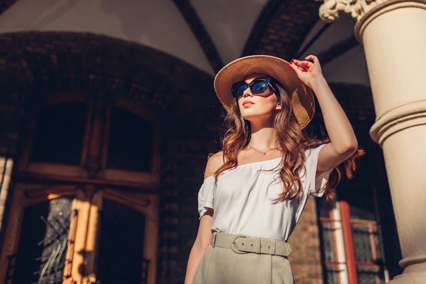Model standing in front of a building holding her hat