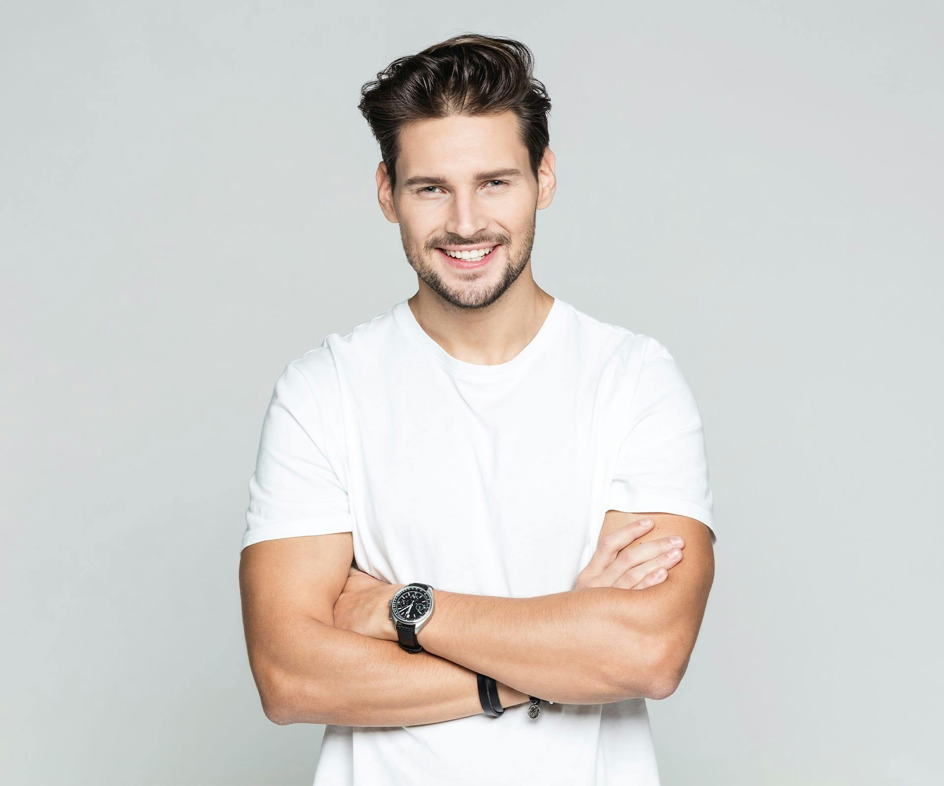 a man smiling and crossing his arms after getting a dental bridge in Bluffton and Hilton Head