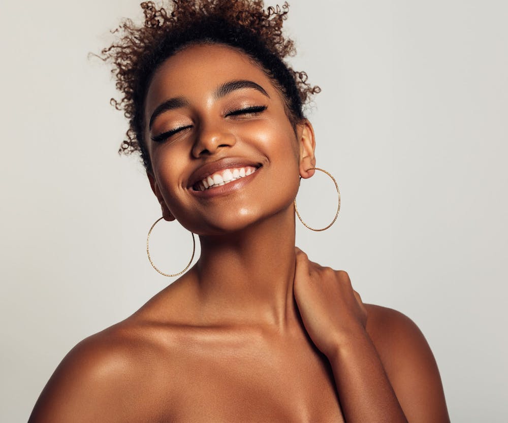 a woman smiling and closing her eyes after getting Invisalign in Bluffton and Hilton Head