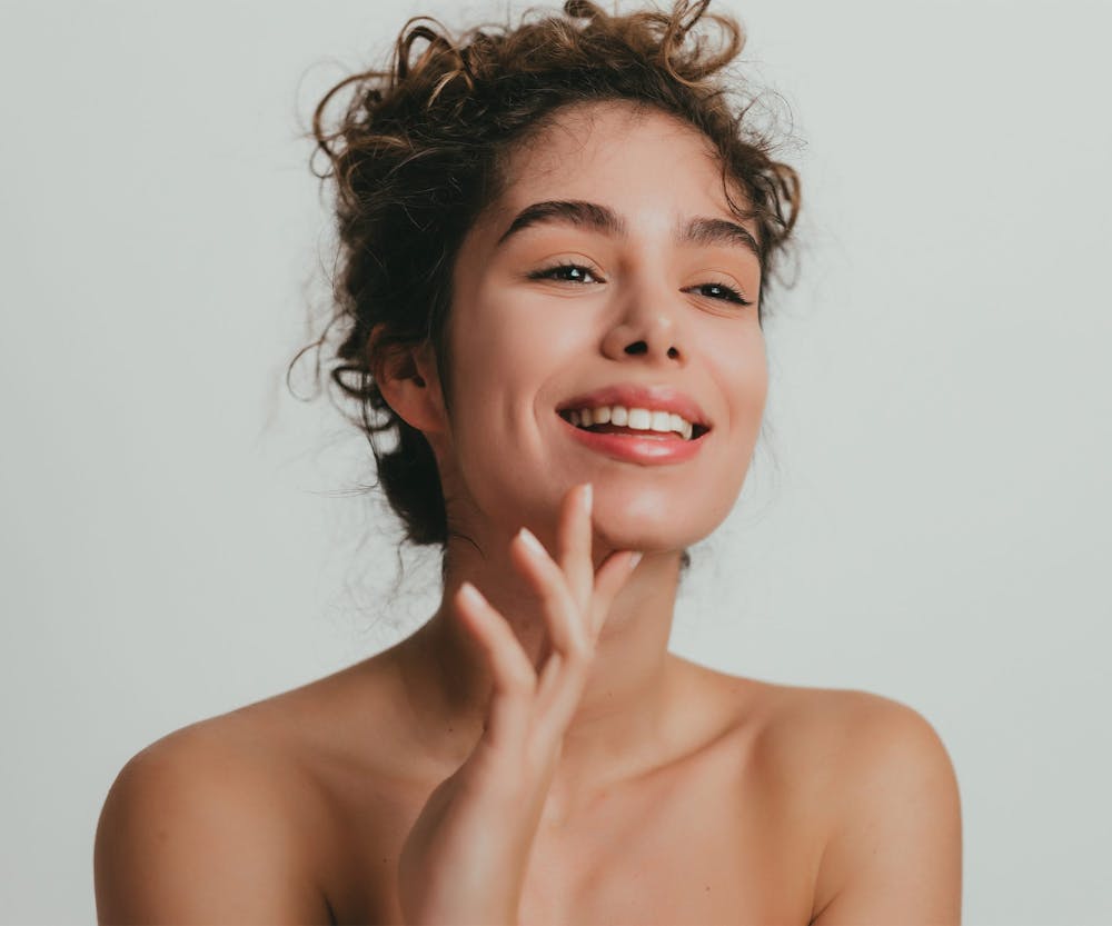 a woman smiling and touching her chin after getting porcelain veneers in Bluffton and Hilton Head