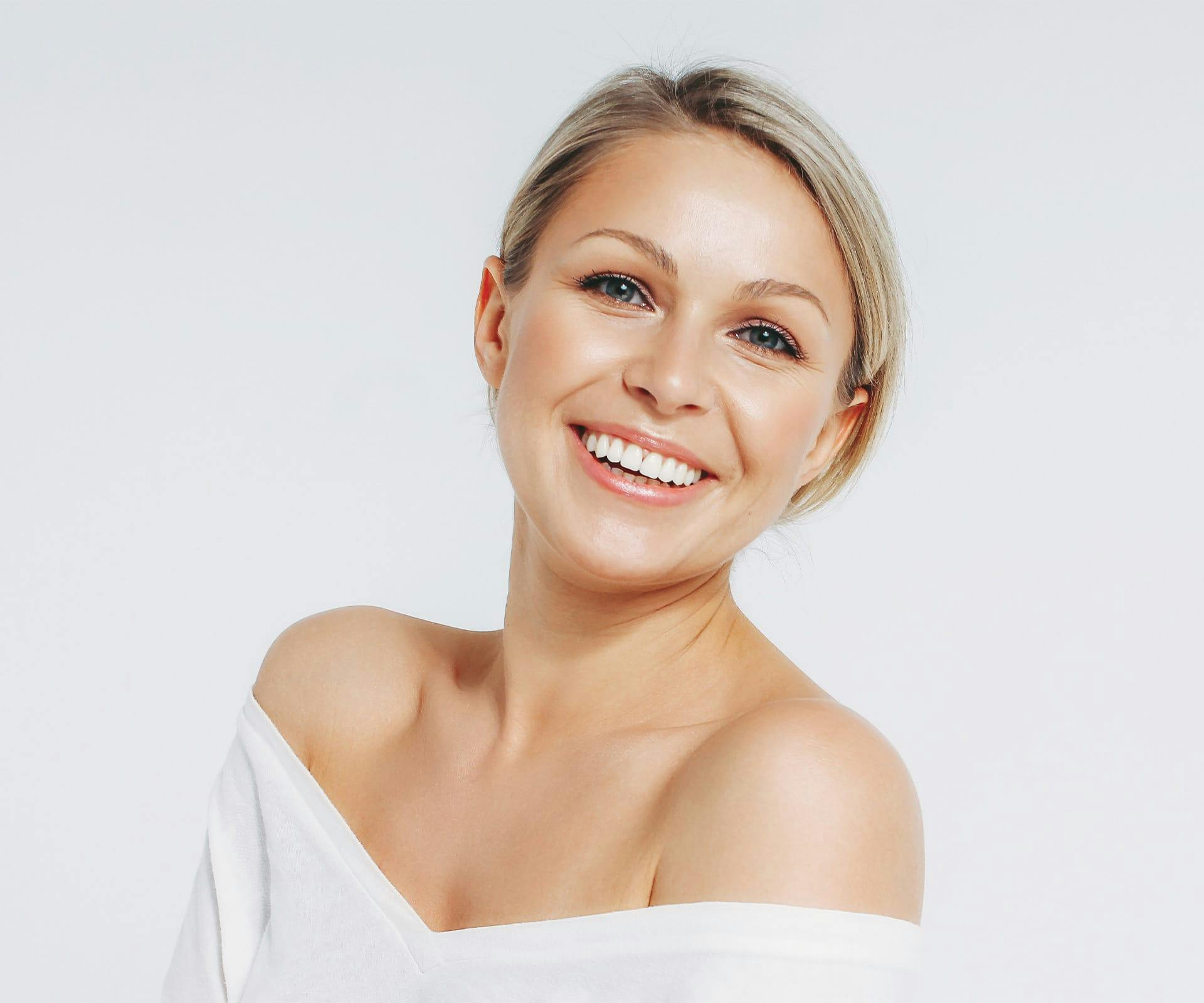 woman in white shirt smiling with her hair tied up