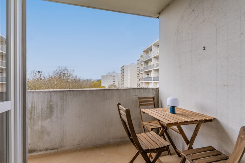 table en bois avec chaises sur balcon cergy