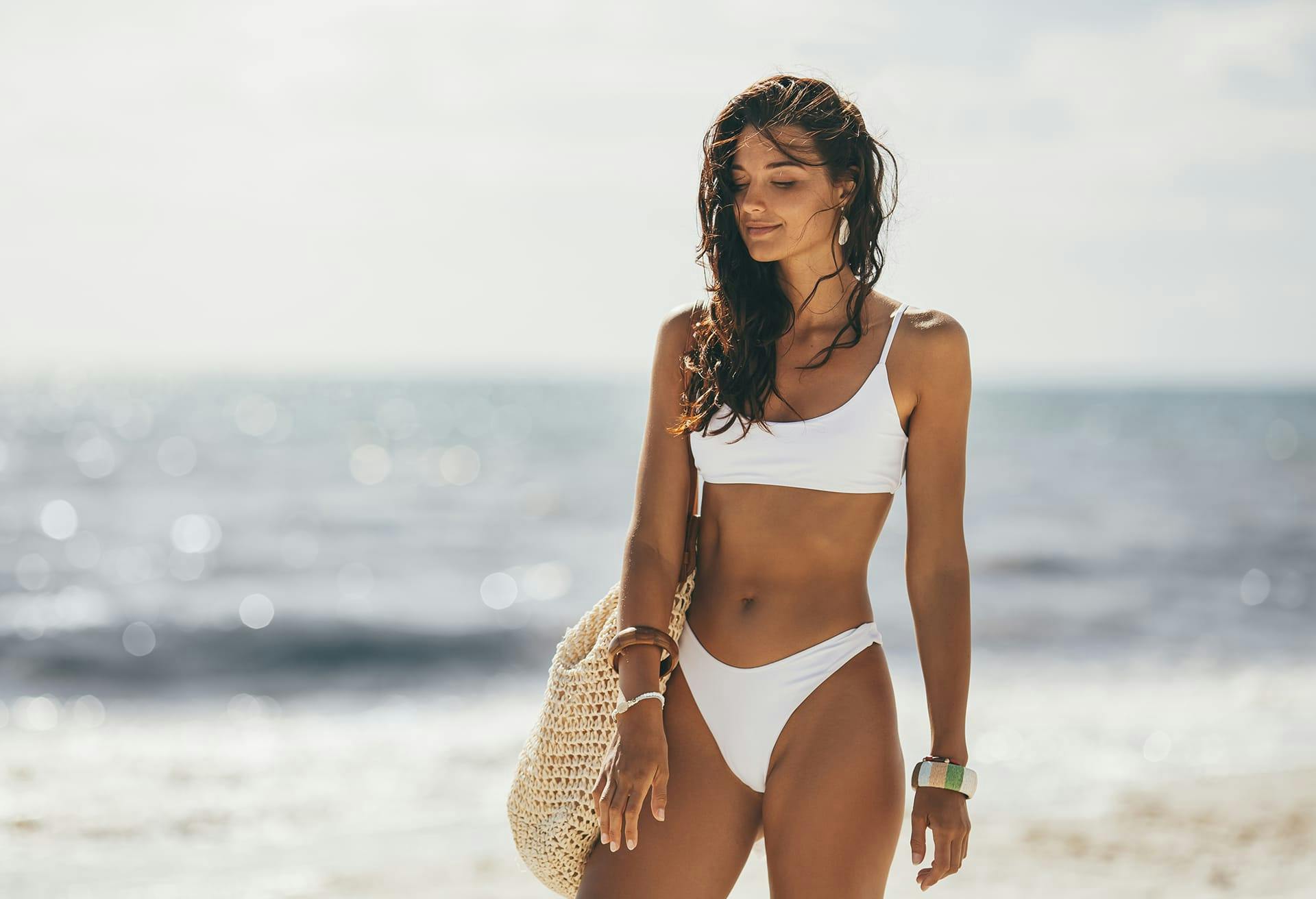 Tan woman in a white bikini at the beach
