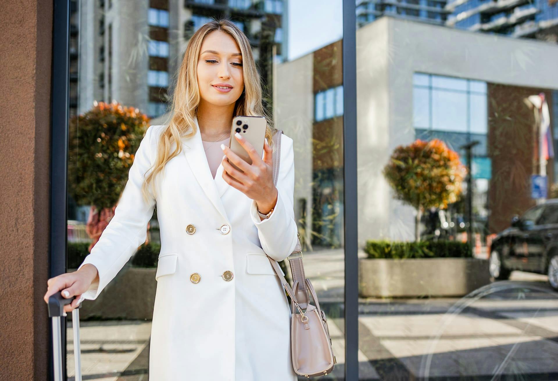 Woman wearing a white blazer looking at her phone