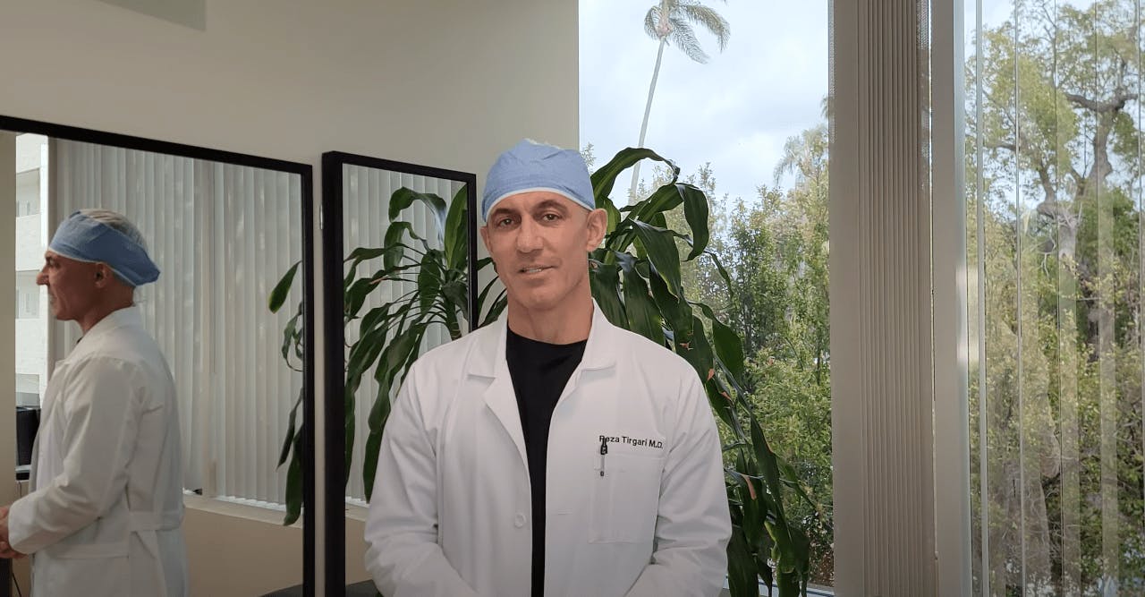 Dr. Tirgari wearing his white doctor's lab coat and a scrub cap