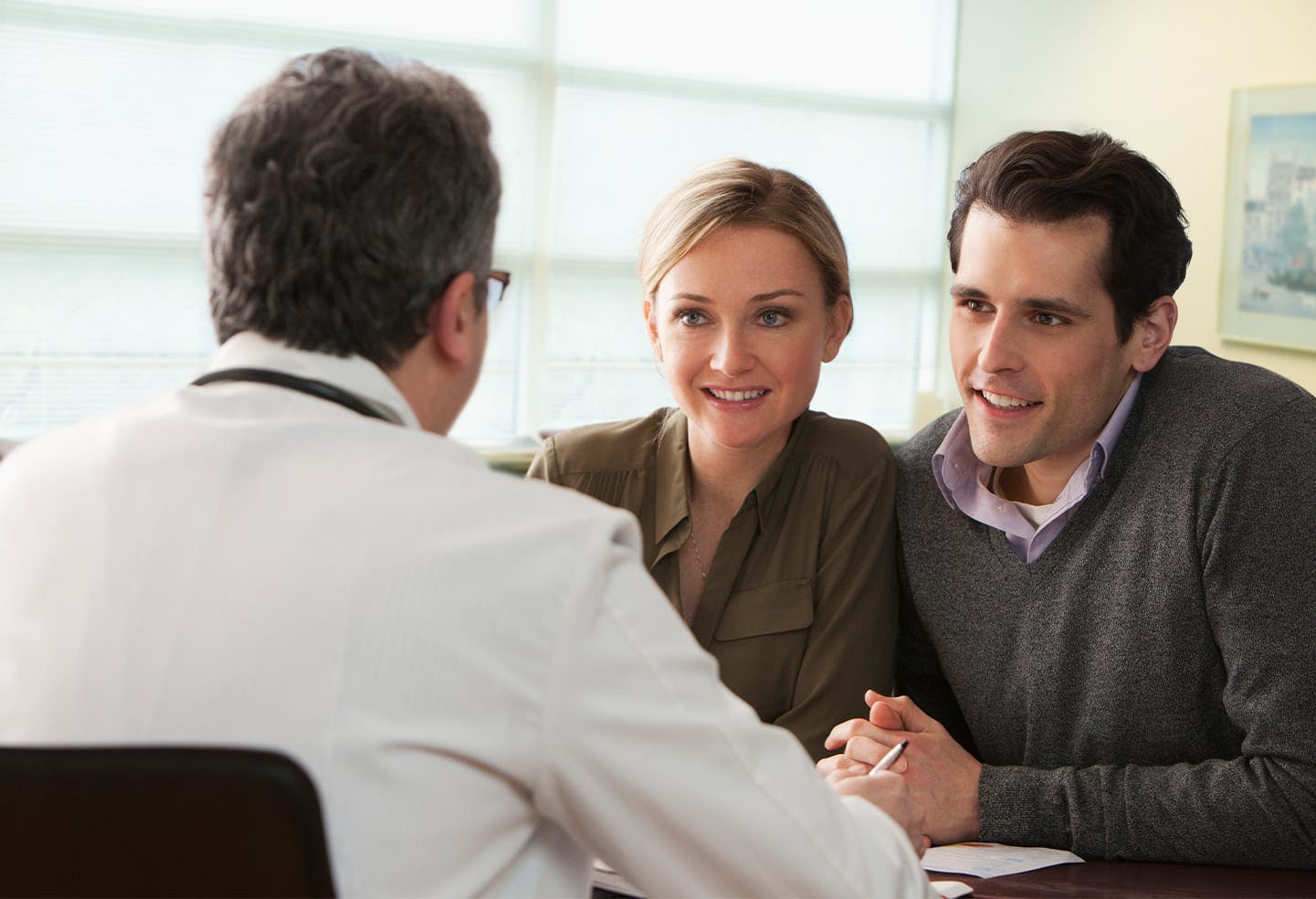 Man and woman sitting at a desk speaking with a doctor