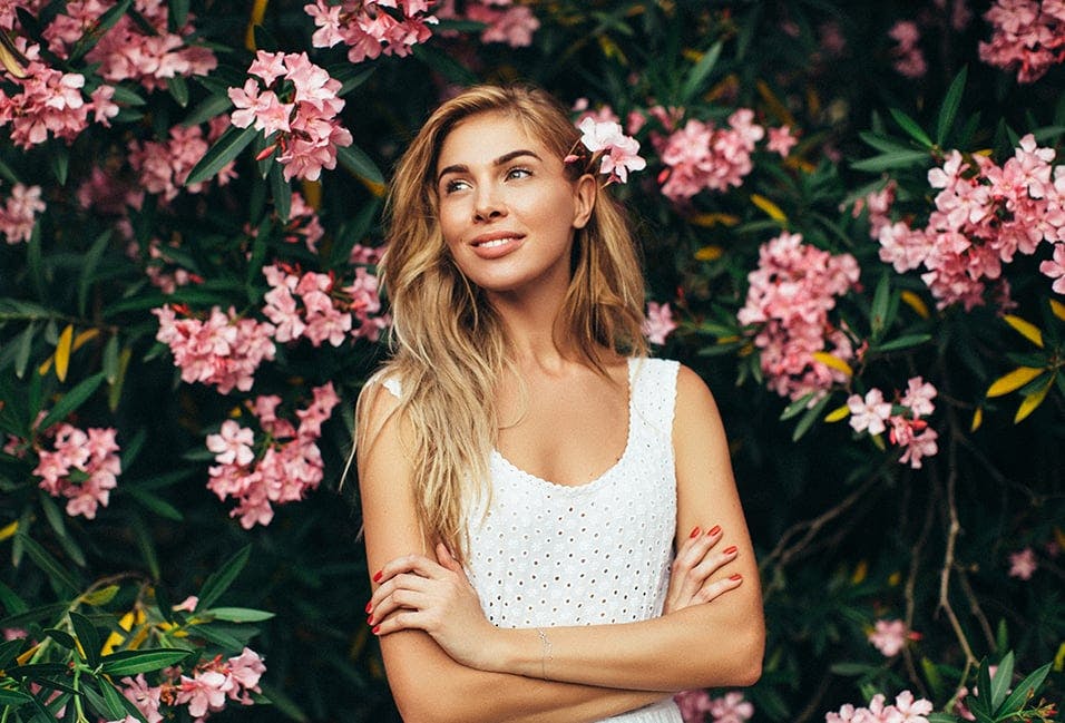 Woman Posing in Front of a Bush with Pink Flowers