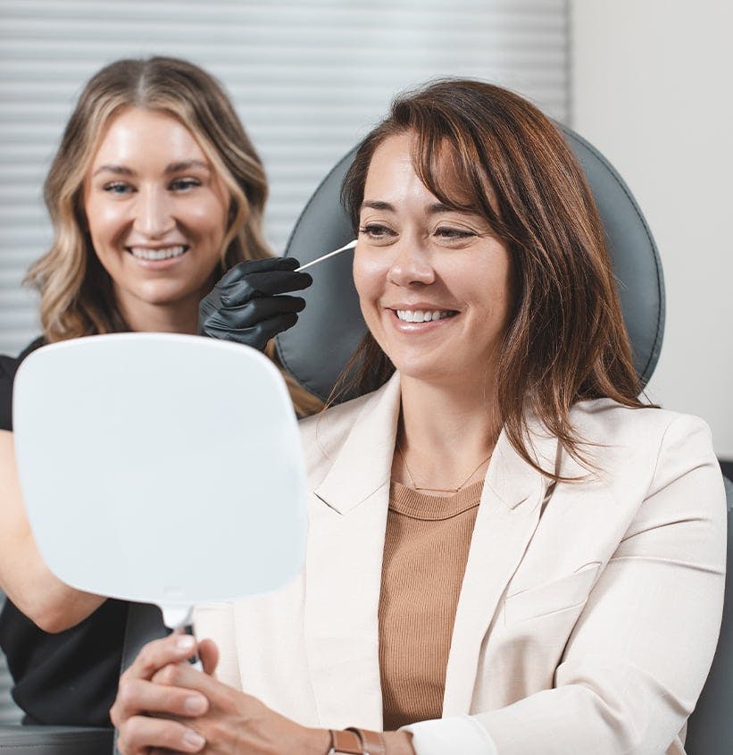 Female patient looking at herself in a handheld mirror