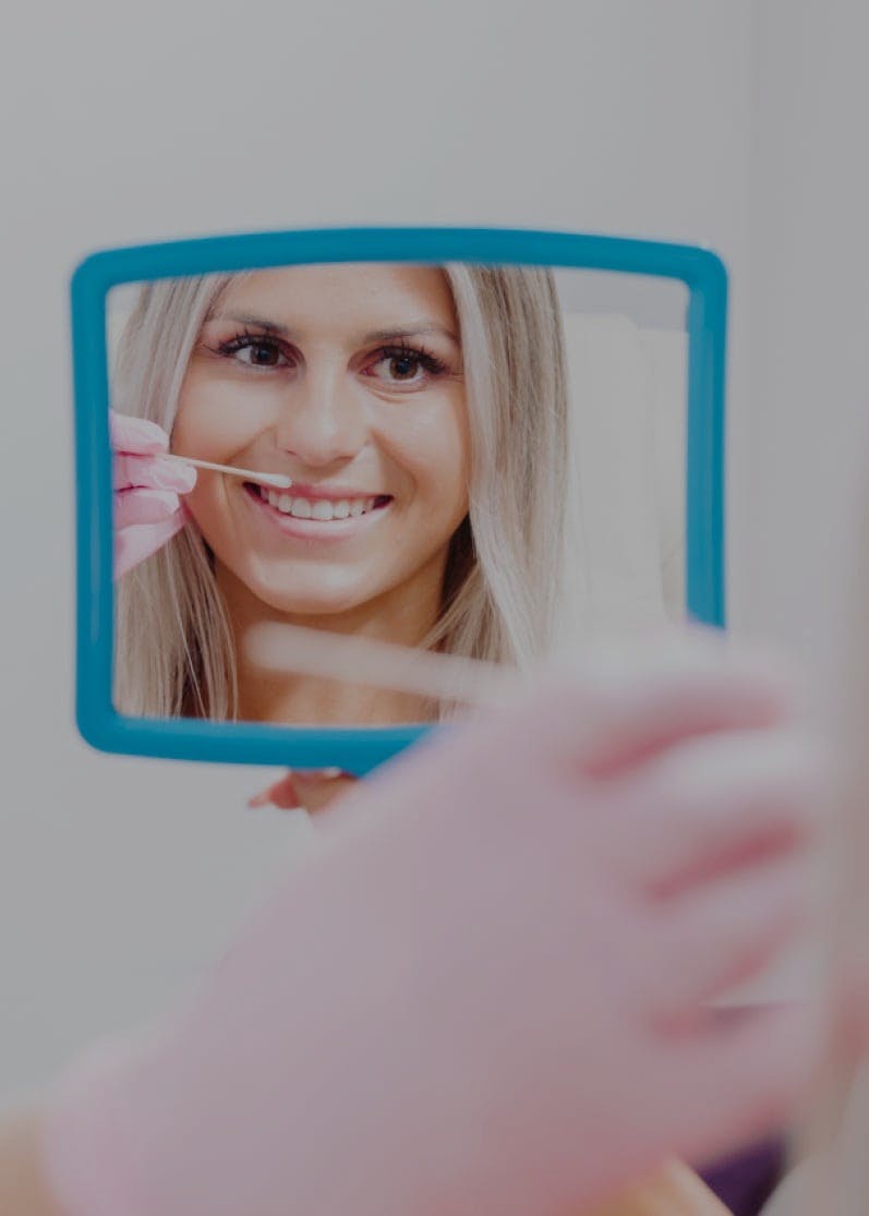 Smiling woman looking in a hand mirror during cosmetic treatment at Flawless Medspa and Wellness, the best medspa in Albuquerque