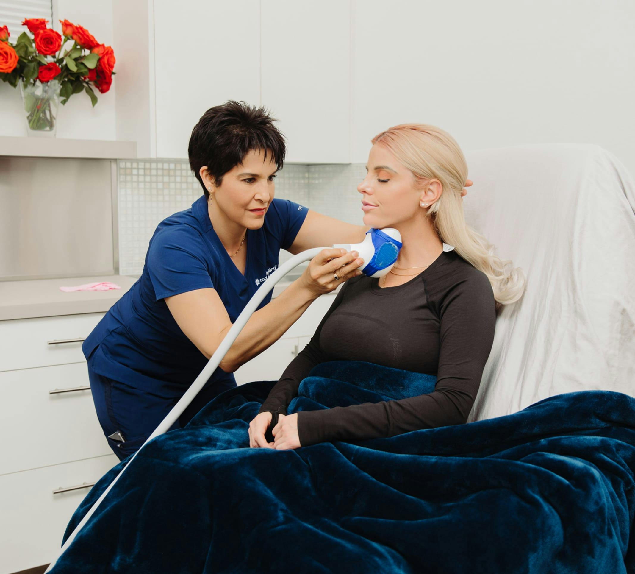 woman in a hospital bed with a nurse using a device