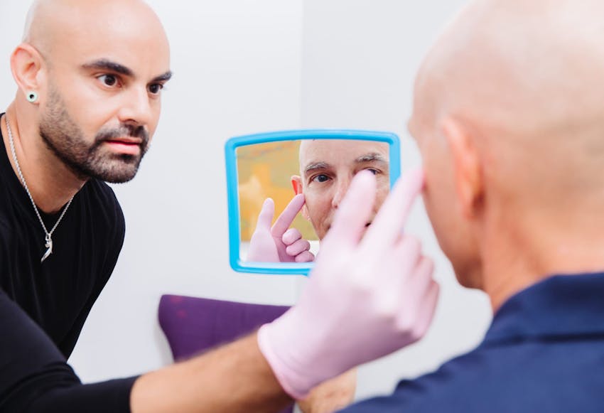 man looking in a handheld mirror