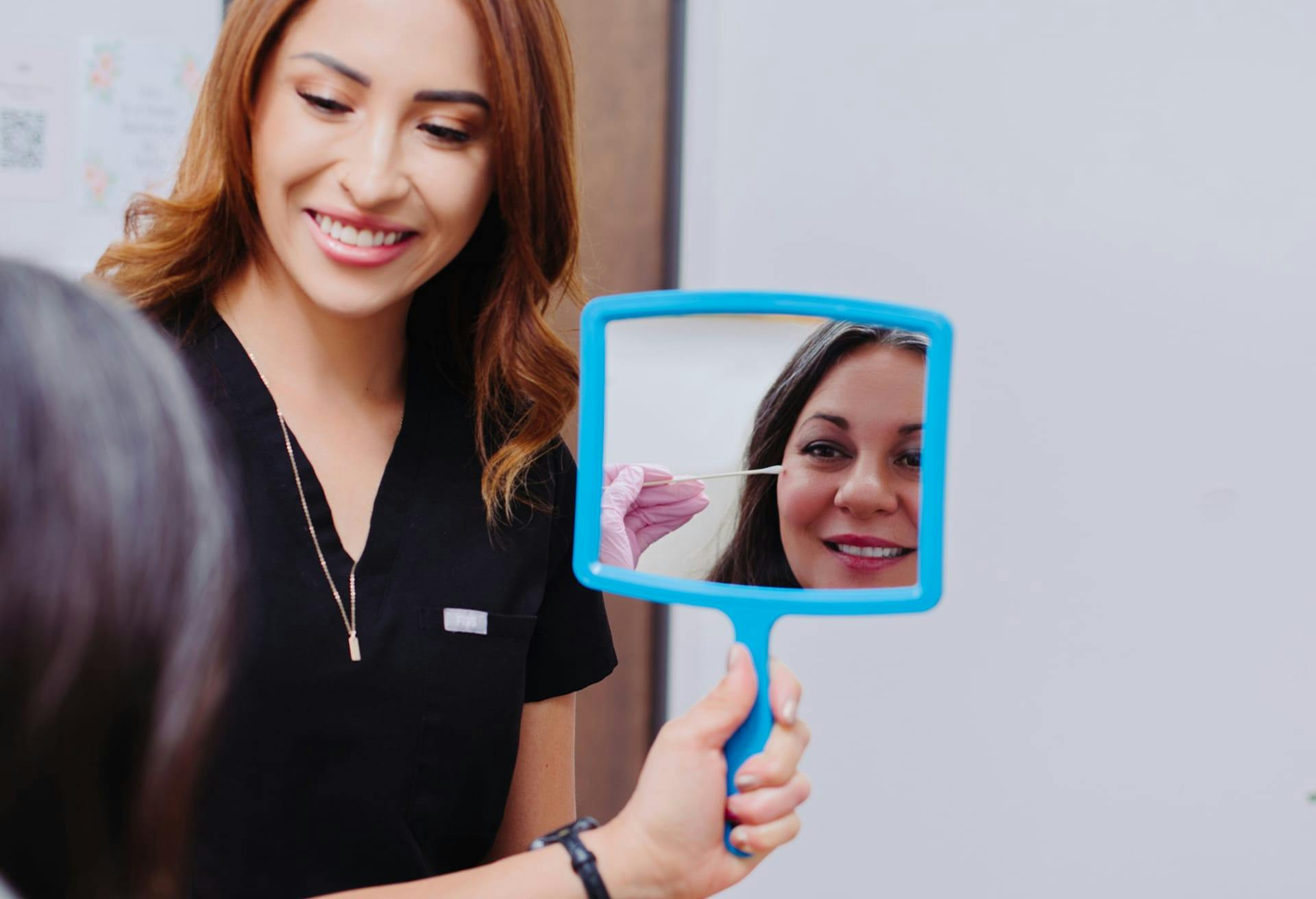 woman looking at her face in a handheld mirror