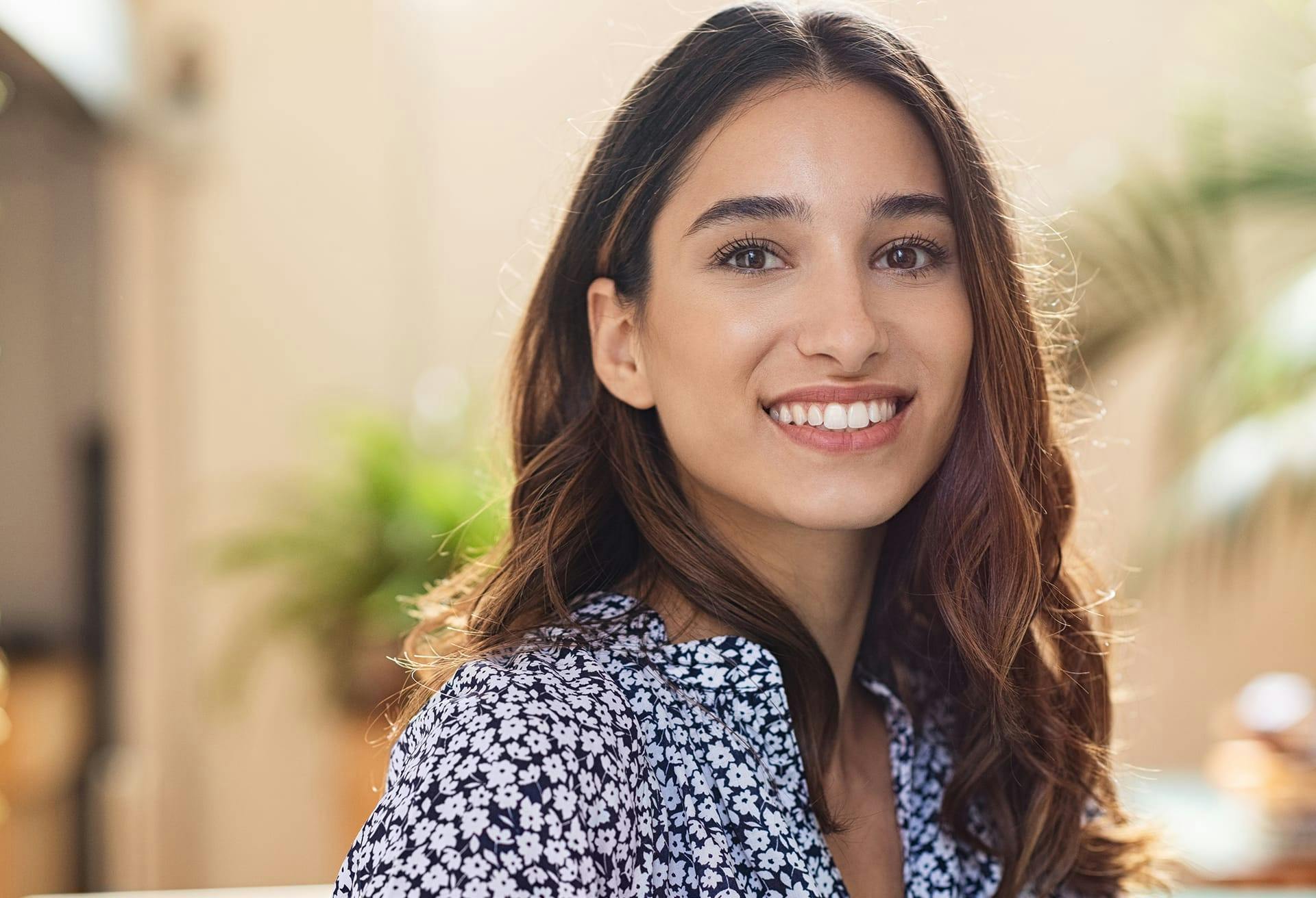 woman smiling while wearing a floral blouse
