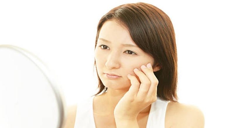 woman looking in a mirror while touching her face