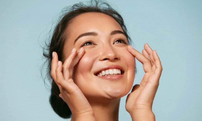 a woman smiling with her hands on her face