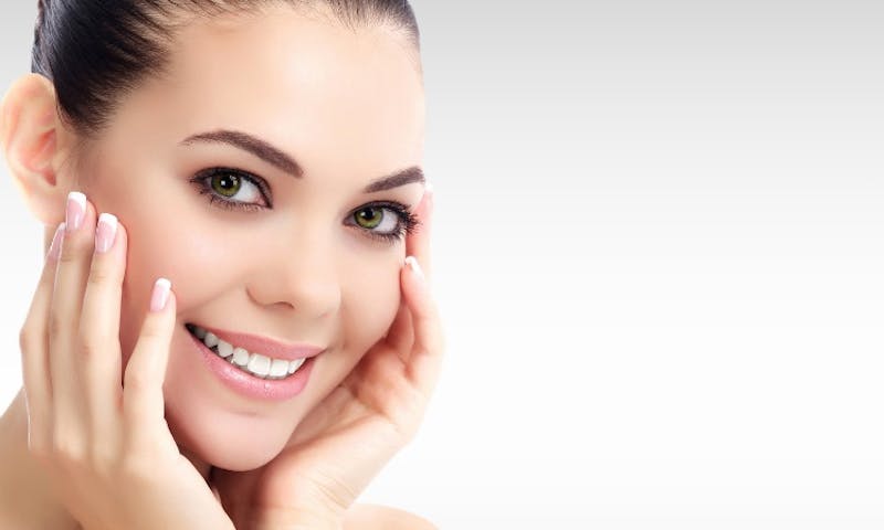 a woman with a smile on her face and hands on her face