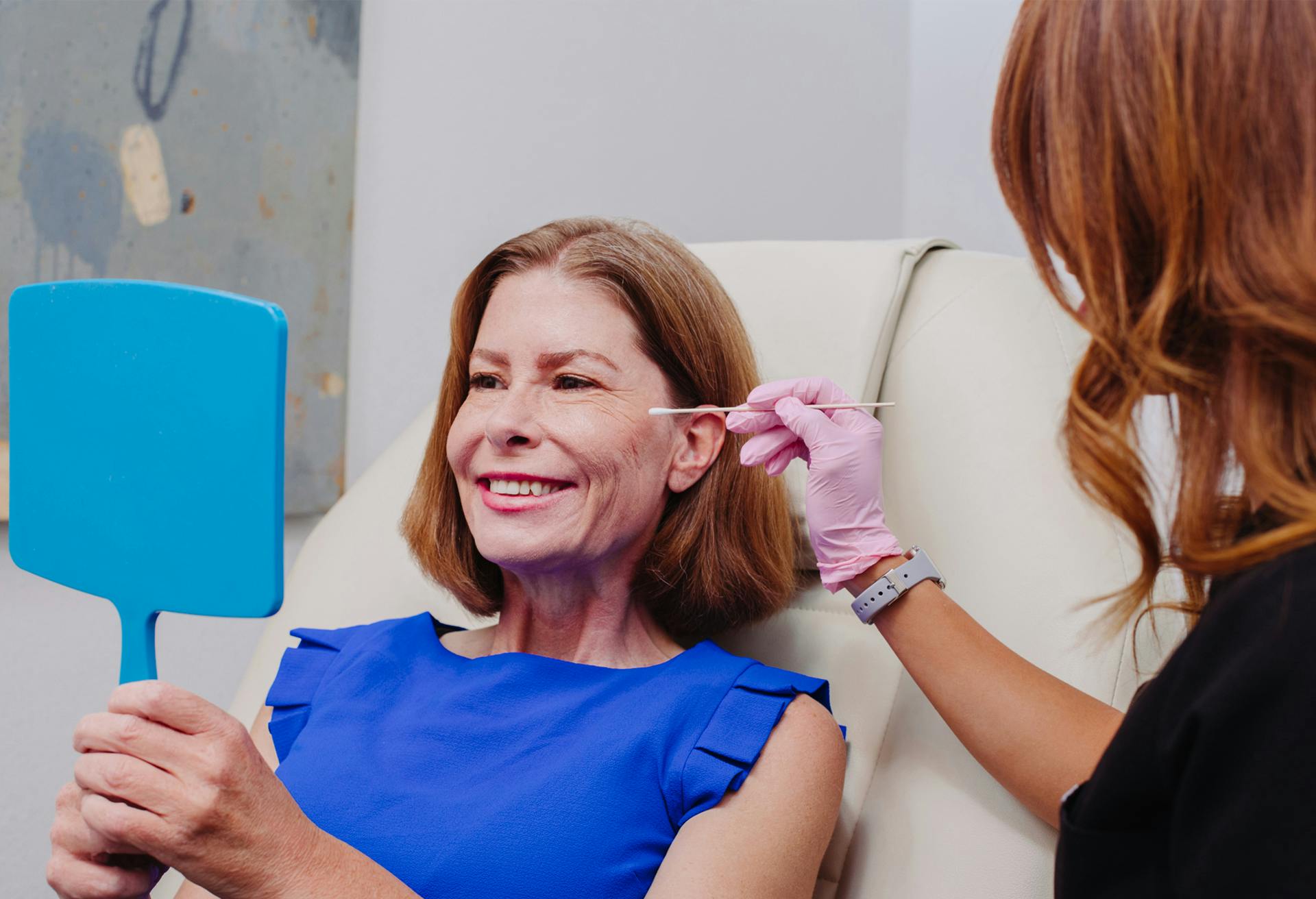 Female patient looking at herself in a handheld mirror