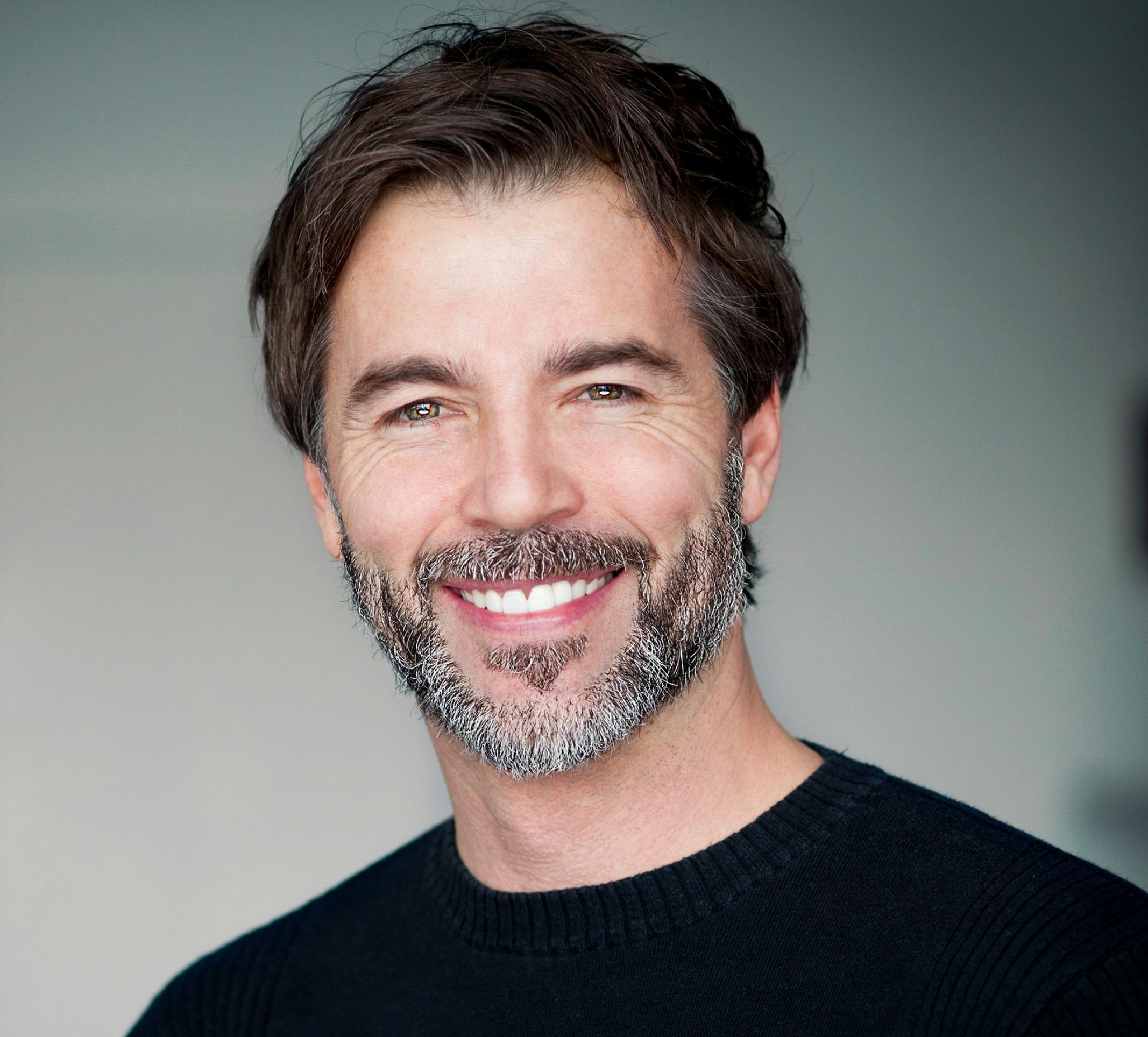 smiling man with beard and mustache wearing black sweater