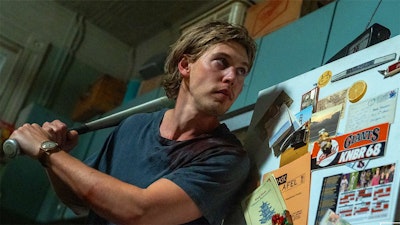 a man with a baseball bat waits behind a refrigerator