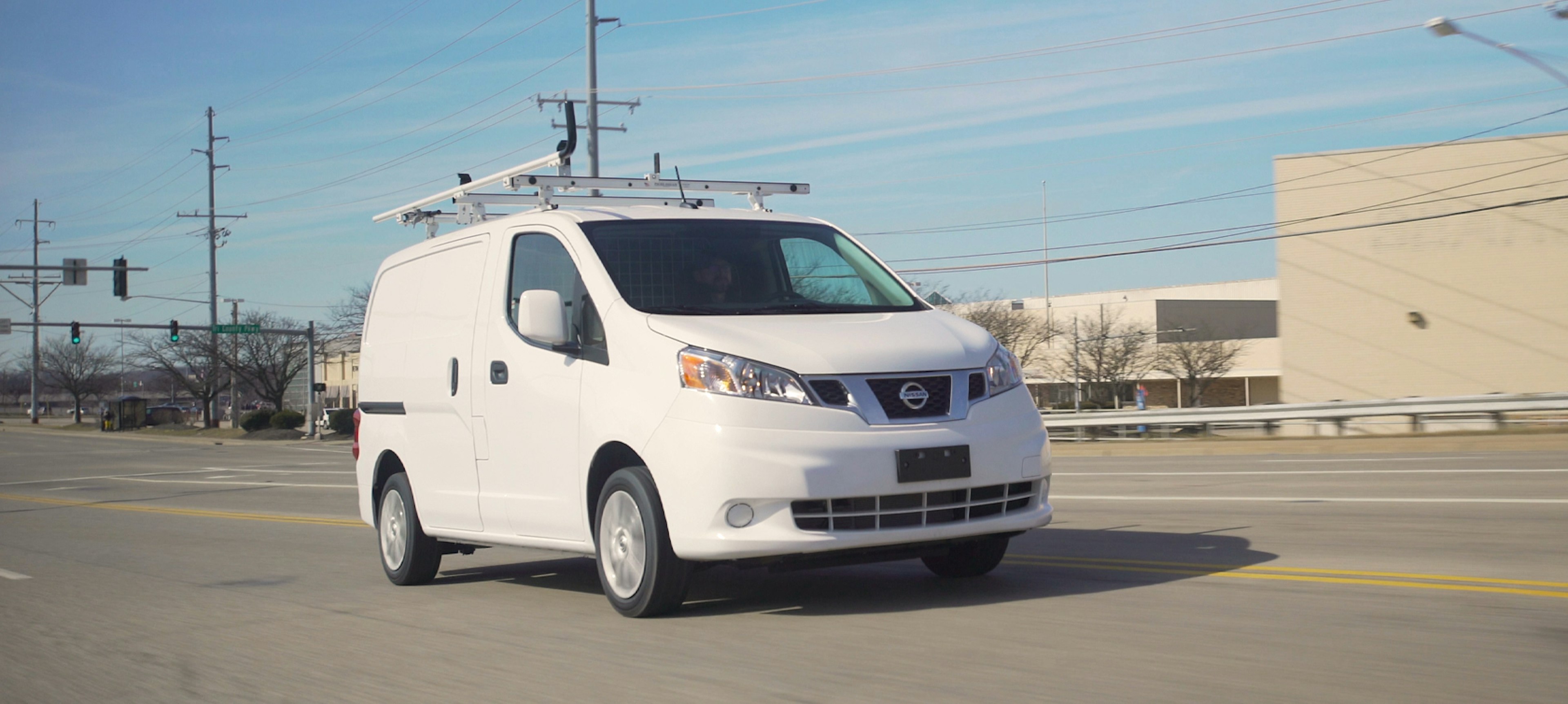 White fleet vehicle with upfit equipment on the road.