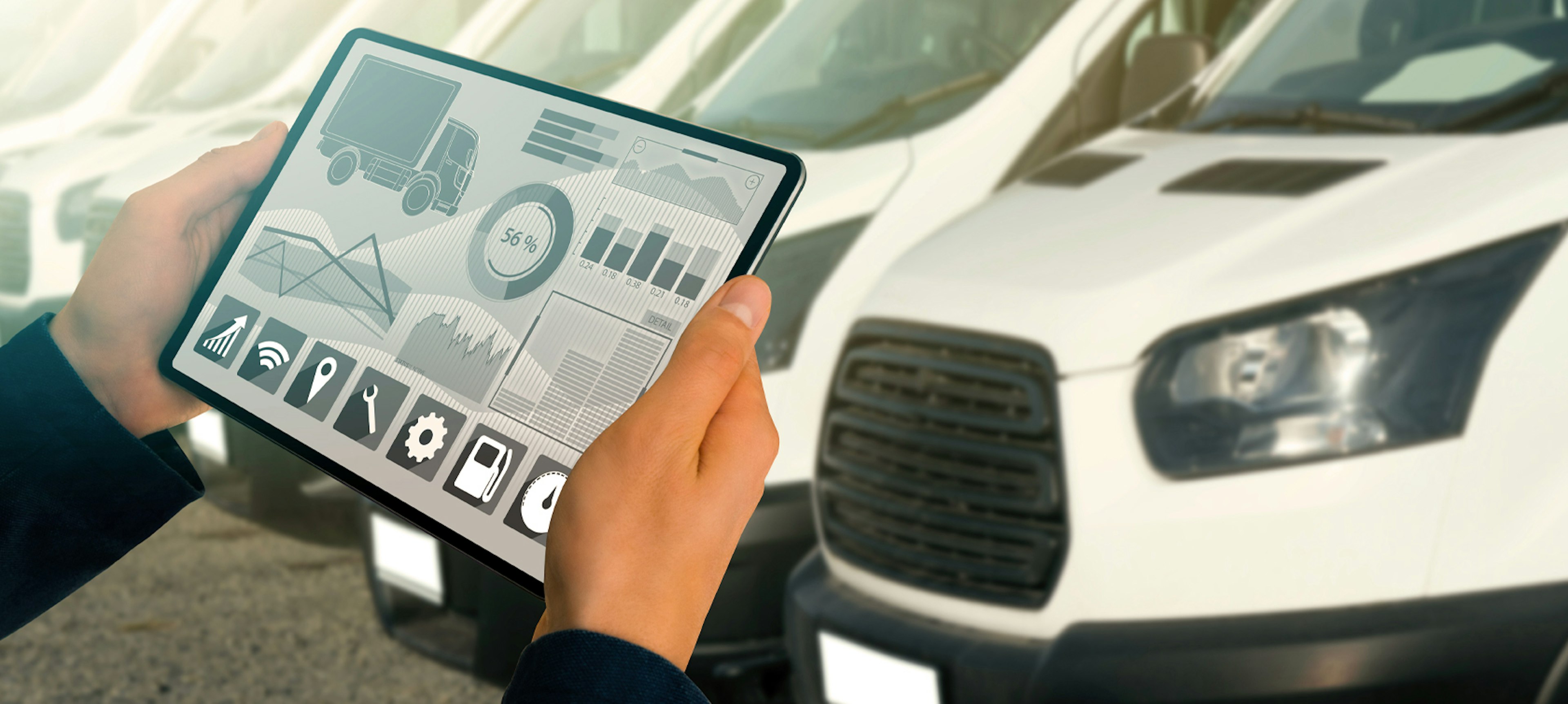Person standing in front of fleet vehicles monitoring vehicle health on tablet