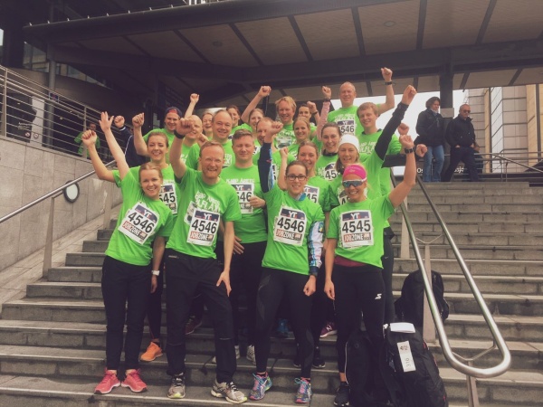 Gruppebiulde av en sporty gjeng jubelende ansatte i treningstøy.