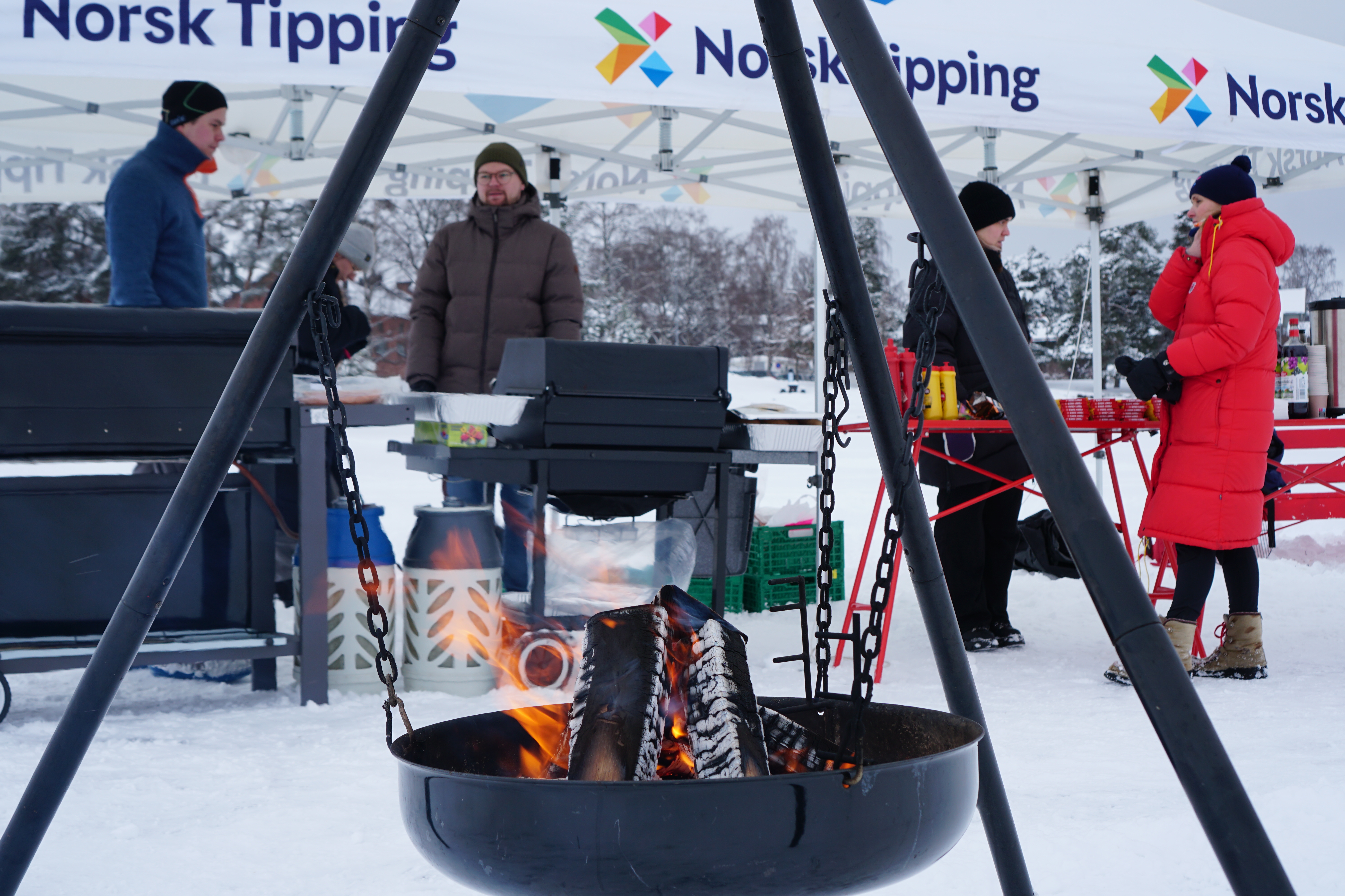 Bålpanne med norsk tipping ansatte i bakgrunn.
