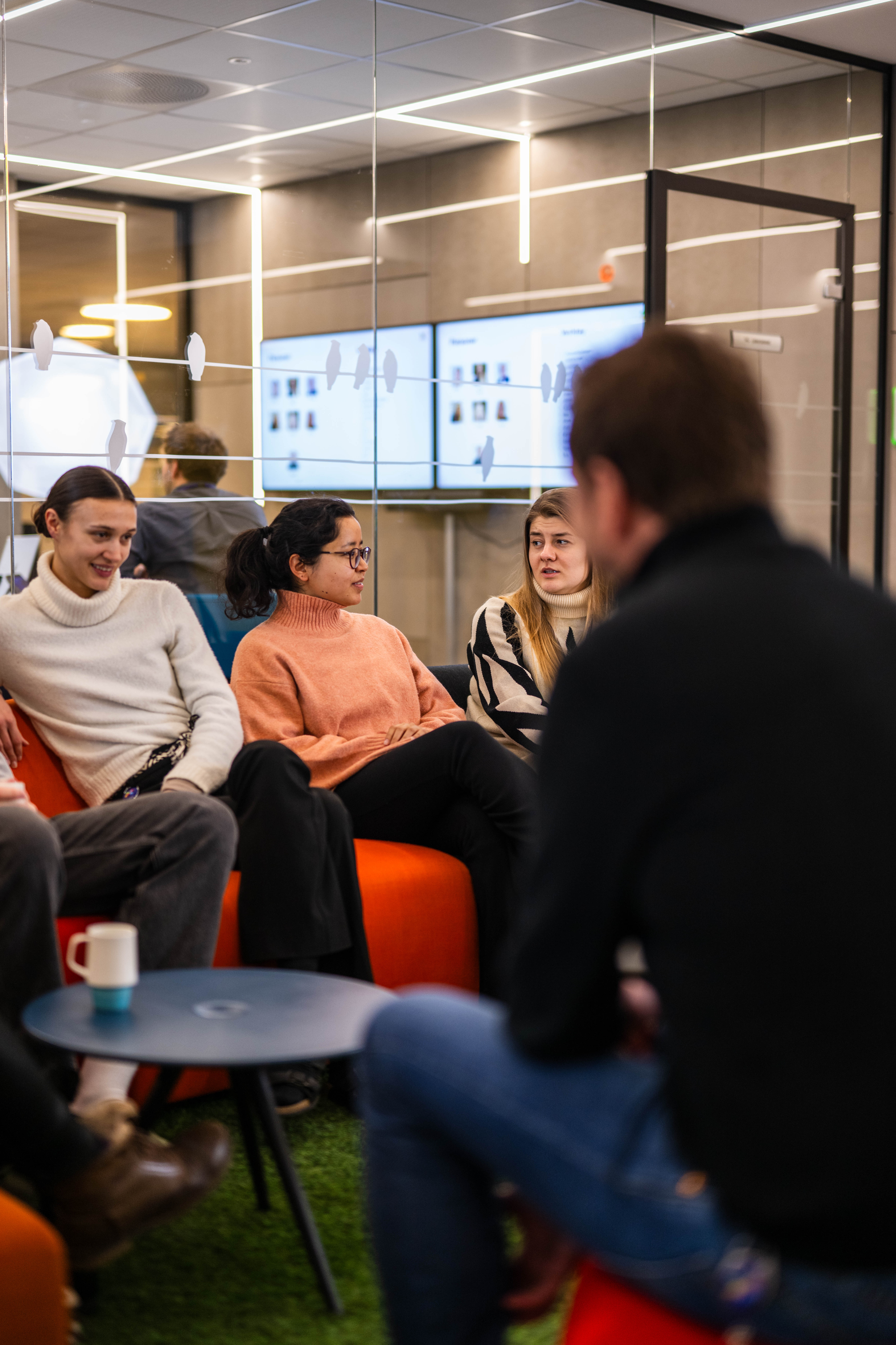 Trainees i Norsk tipping sitter på en sofa og snakker sammen.
