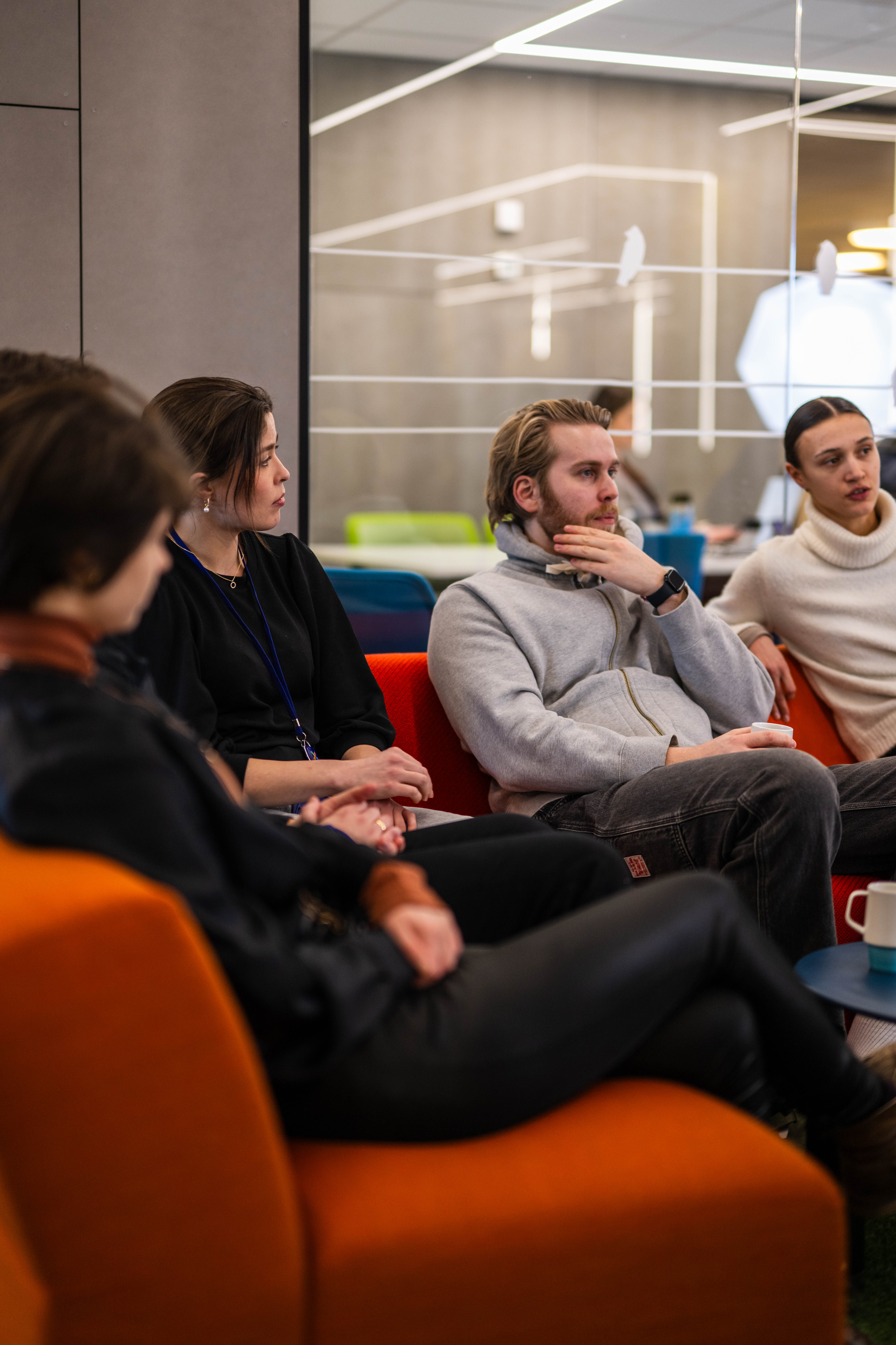 En gruppe personer sitter i en moderne lounge med fargerike møbler