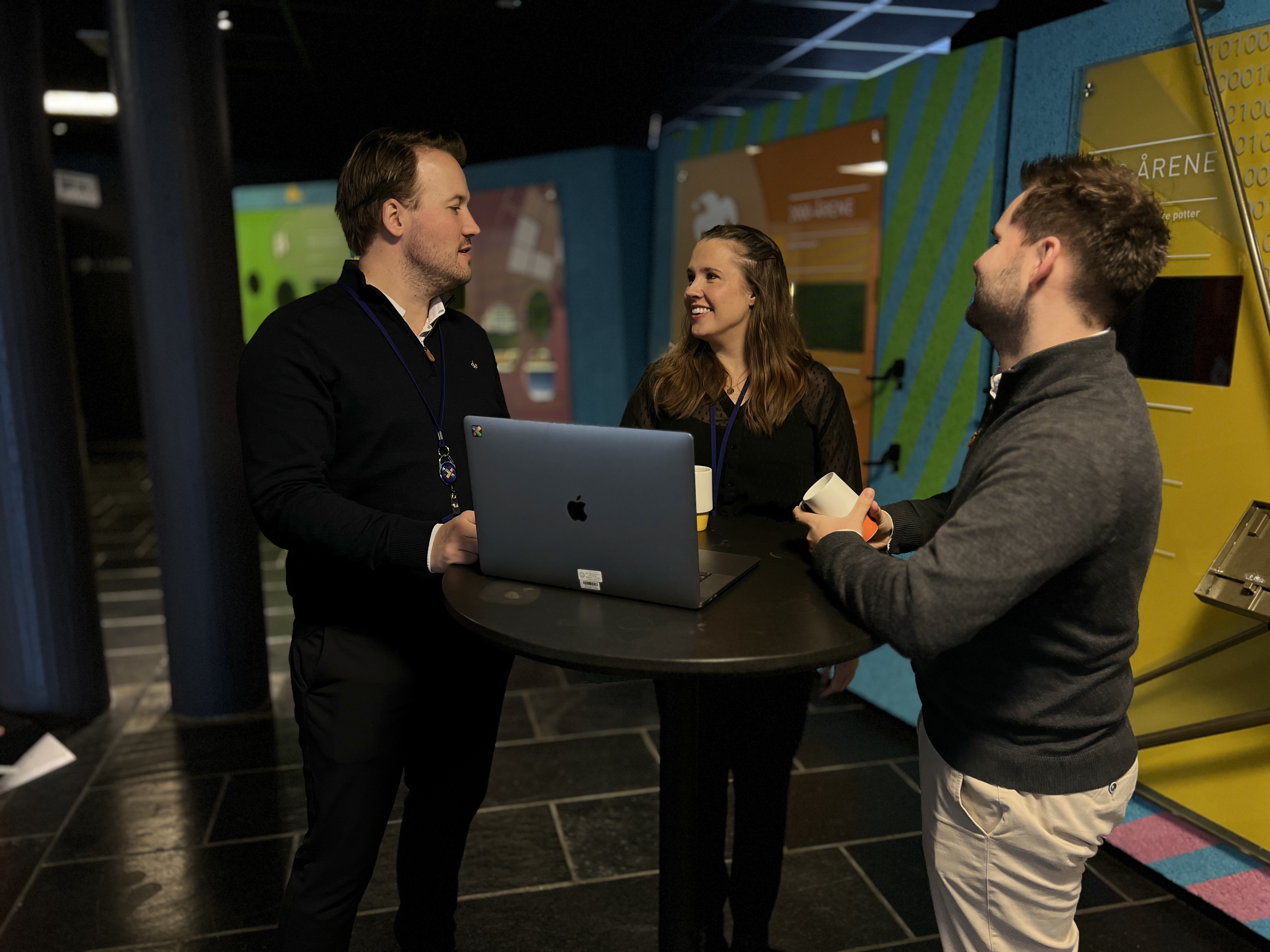 Tre Norsk Tipping ansatte står samlet og snakker sammen.