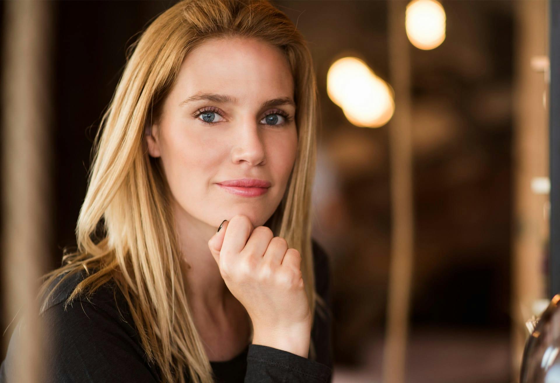 blonde model with her hand up to her chin