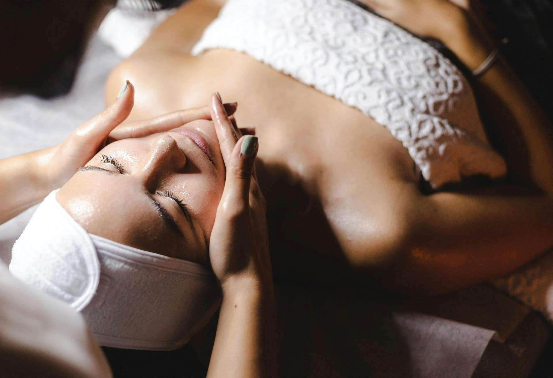 an image of a woman getting a facial laying on a table in a white towel
