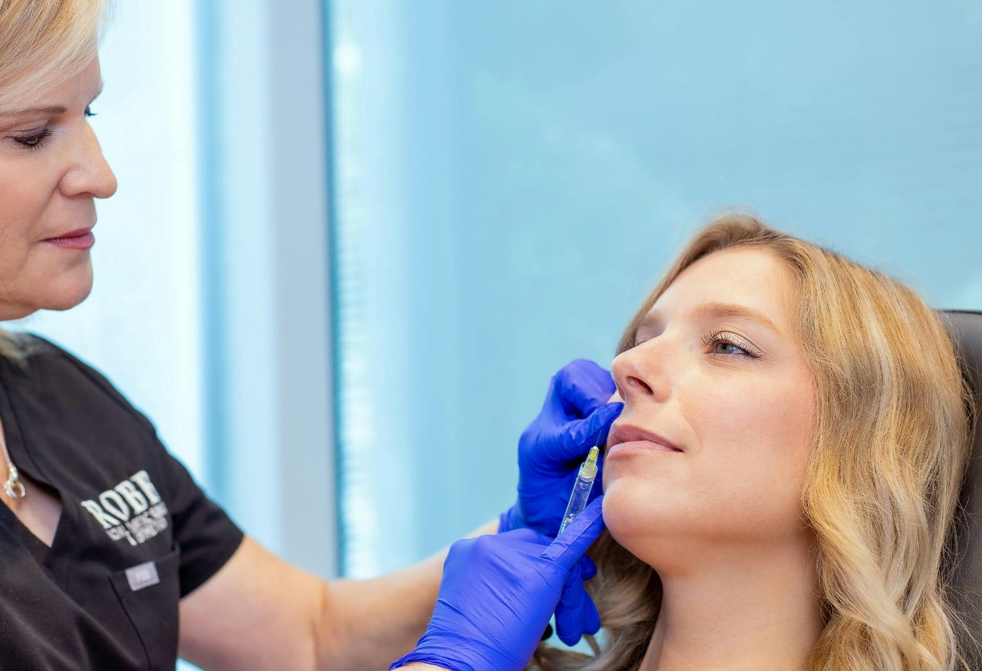 a blonde patient receiving an injectable treatment to her lips