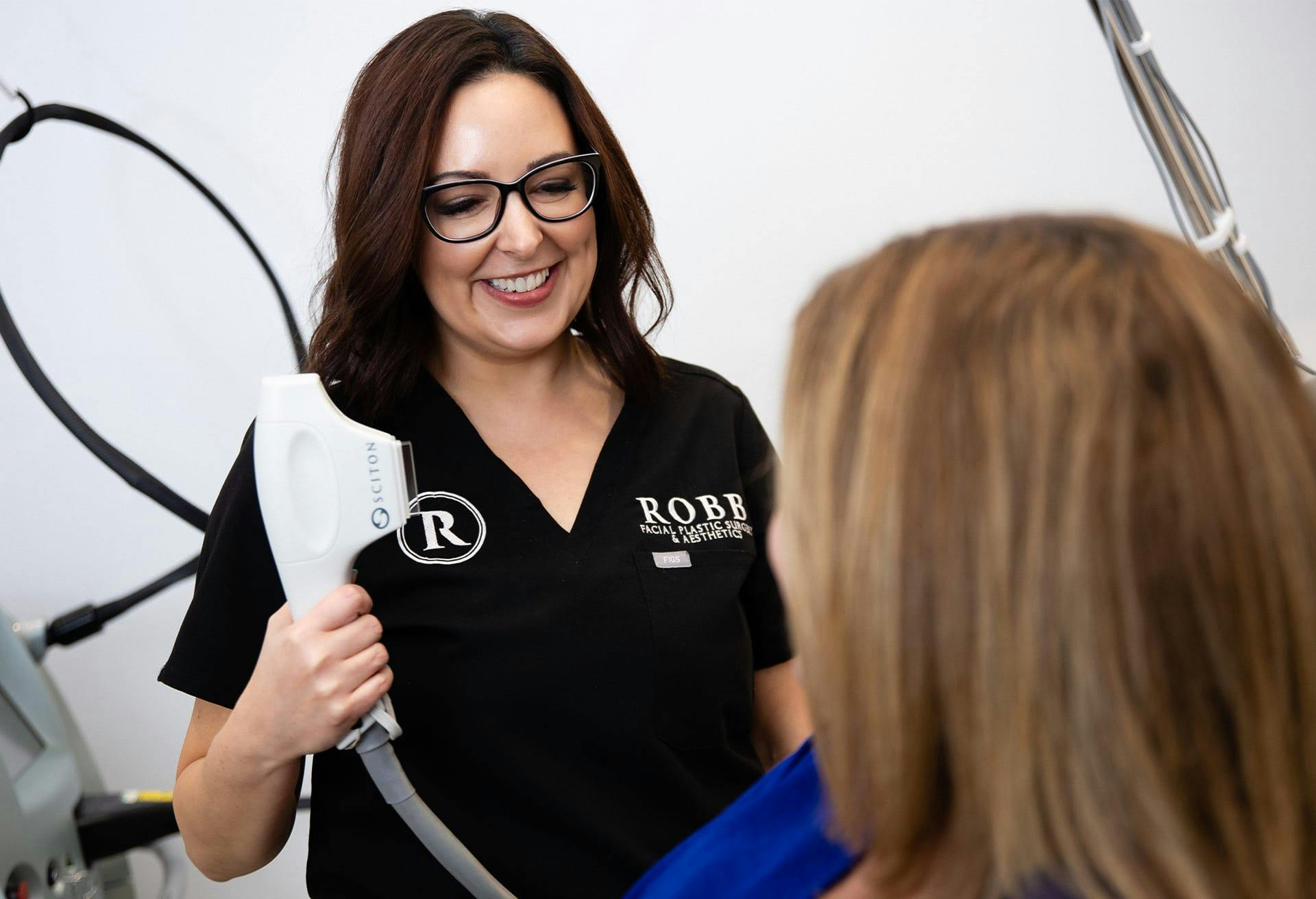 An image of a staff member holding the sciton device smiling at a patient