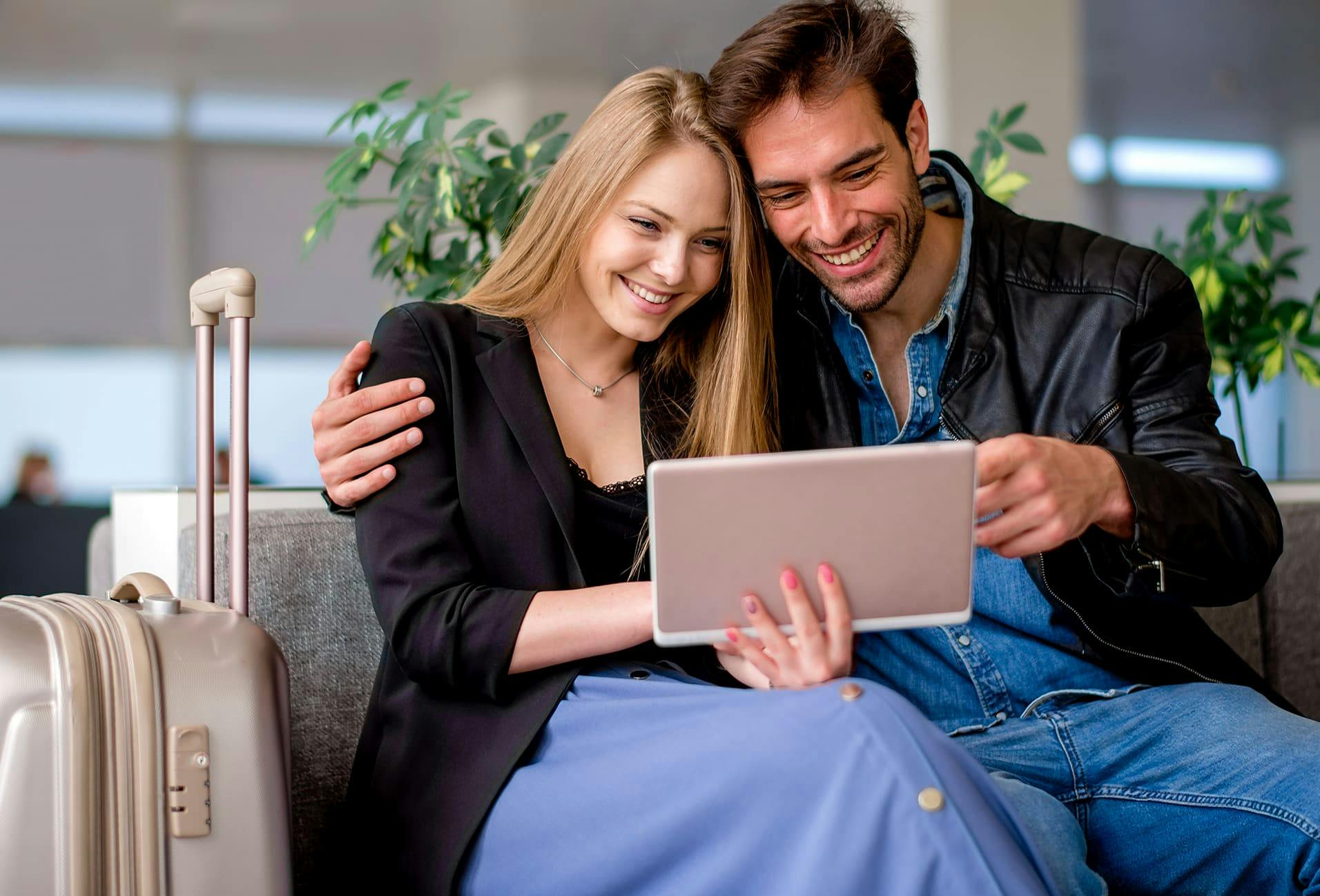 Couple holding each other smiling and looking at laptop
