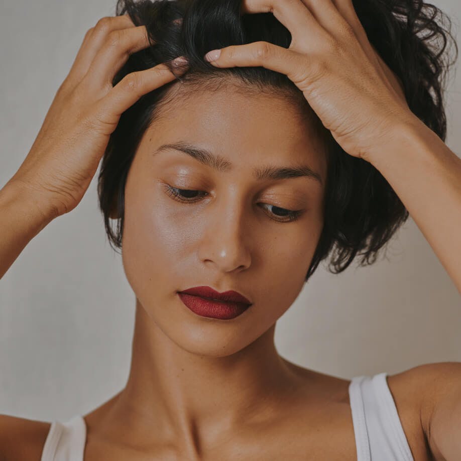 Woman looking down and running hands through her hair