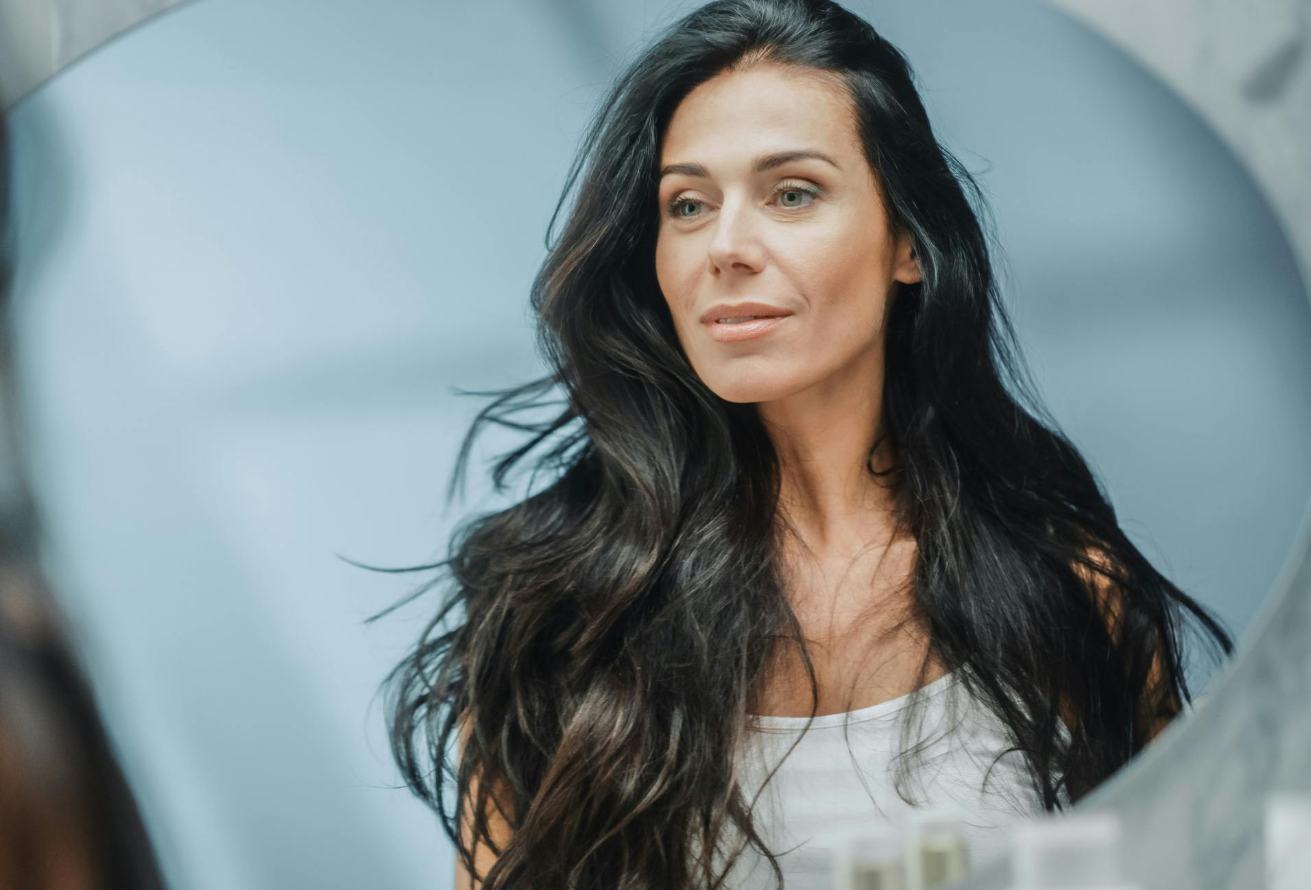 woman looking at face in mirror